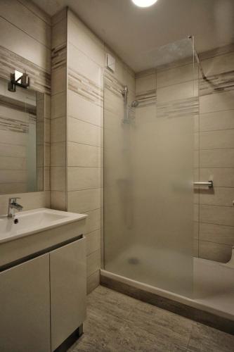 a bathroom with a shower and a sink and a tub at La chouette verte in Granville