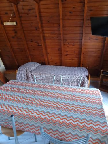 a bed in a room with a table with a blanket at Cabañas Wencesmar in Hipólito Yrigoyen