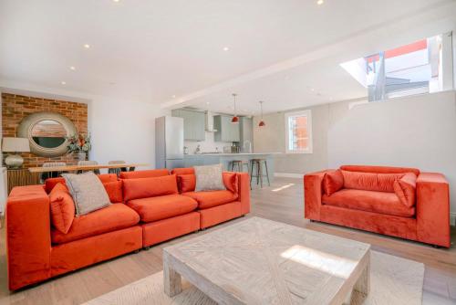 a living room with two orange couches and a kitchen at 3-Bedroom House in Wimbledon with Roof Terrace & Free Parking in London