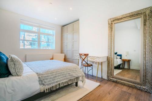 a bedroom with a bed and a mirror at 3-Bedroom House in Wimbledon with Roof Terrace & Free Parking in London