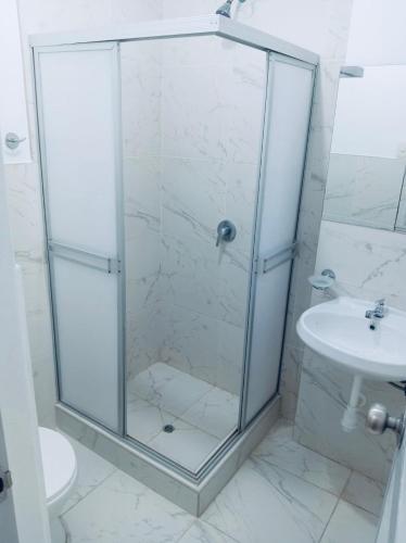 a shower with a glass door next to a sink at OOK Home in Canoas de Punta Sal