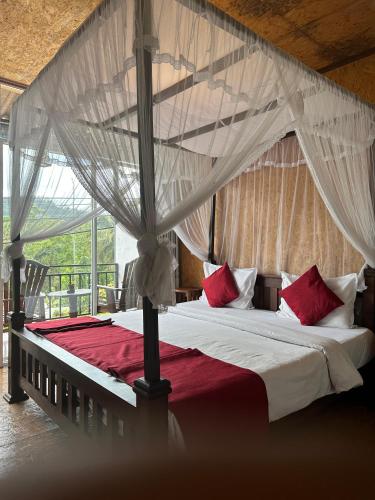a bedroom with a canopy bed with red and white pillows at Ella Nature Life Guest & Restaurant -Free Pickup from Ella in Ella