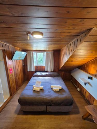 a large bed in a room with wooden walls at Hotel Surprise Bariloche Centro con Desayuno y Restaurante in San Carlos de Bariloche