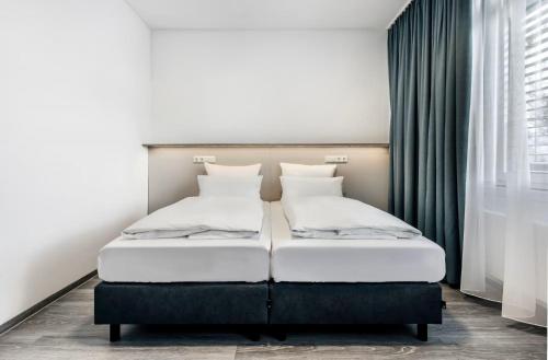 a bedroom with two beds and a window at Oskar25 Aparthotel in Ismaning