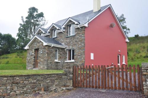 una casa rossa con un muro di pietra e un muro di mattoni di Grace's Landing a Sneem