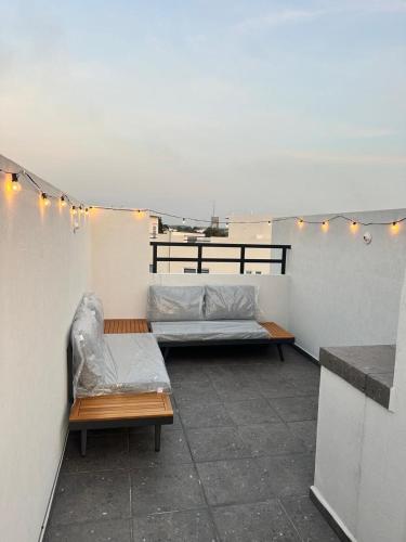 a patio with two beds and lights on a wall at La Casa de Coco in Tlayacapan