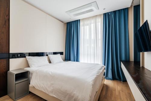 a bedroom with a large bed and blue curtains at Coastal Residences by In Property in Bečići