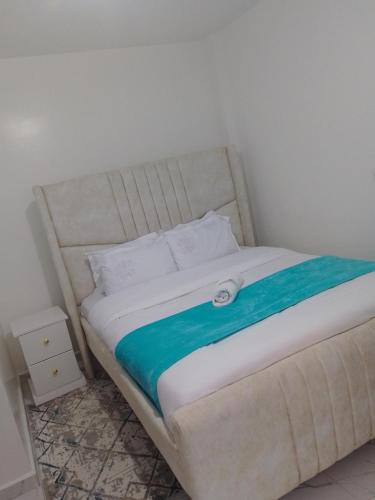 a white bed with a blue blanket on it at Modern staycation -ruaka in Ruaka