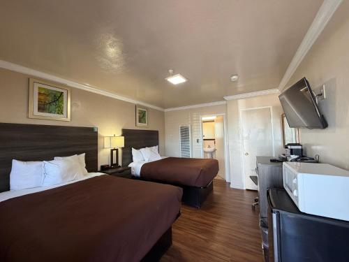 a hotel room with two beds and a flat screen tv at SurfSide Stay in Morro Bay
