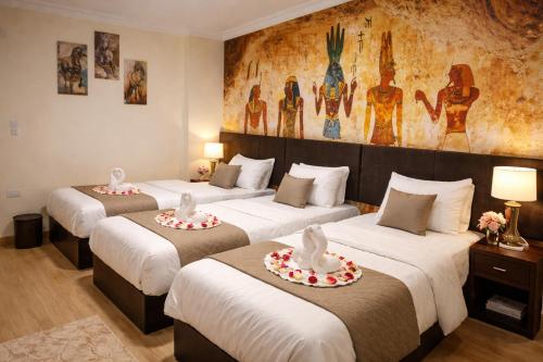three beds in a room with a painting on the wall at phoenix Pyramids- roof top in Cairo