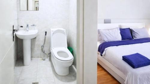 a bathroom with a toilet and a sink next to a bed at HD Residential Apartment , Bole Dembel in Addis Ababa