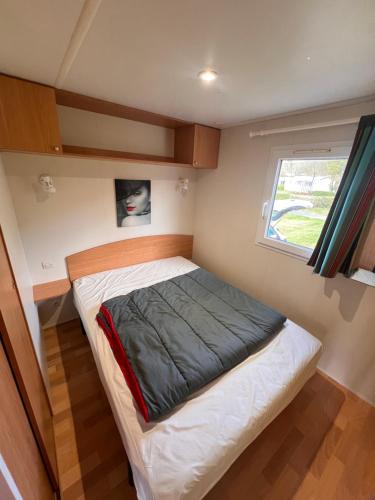 a bed in a small room with a window at Mobile Home à Louannec in Louannec