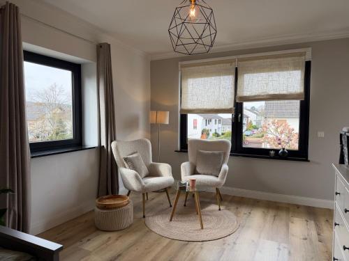 a living room with two chairs and a table and windows at WohlfühlWerk L4 in Mechernich