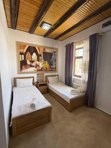 a bedroom with two beds and a painting on the wall at Guest house Afsona old city in Bukhara