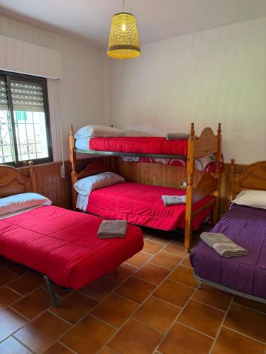 a room with four bunk beds with red sheets at VILLA LÚA in Cartaya