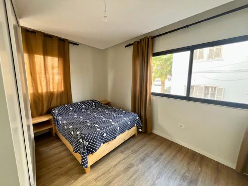 a bedroom with a bed and a large window at JLKM Mindelo Central Residence in Mindelo