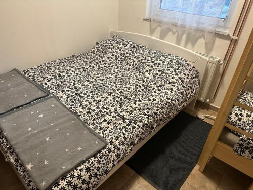 a bed with a black and white blanket on it at Apartments Barbra - Robinson life in Slovenj Gradec