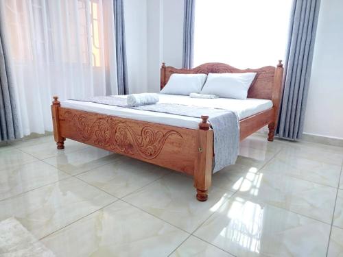 a bedroom with a wooden bed in a room at Laxury3BR Mins to Nyali Beach fast WiFi Netflix AC and Free Parking Near wild waters in Mombasa