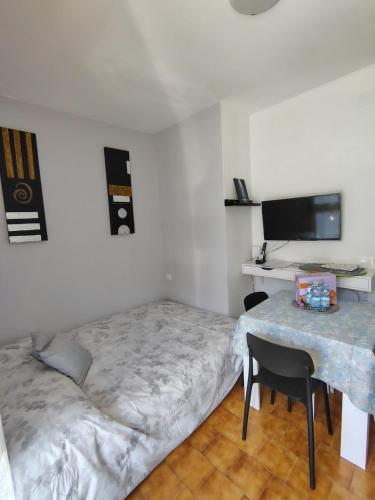 a bedroom with a bed and a table and a tv at "Le Betulle 10" cinque minuti dal mare, Self check in in Bibione
