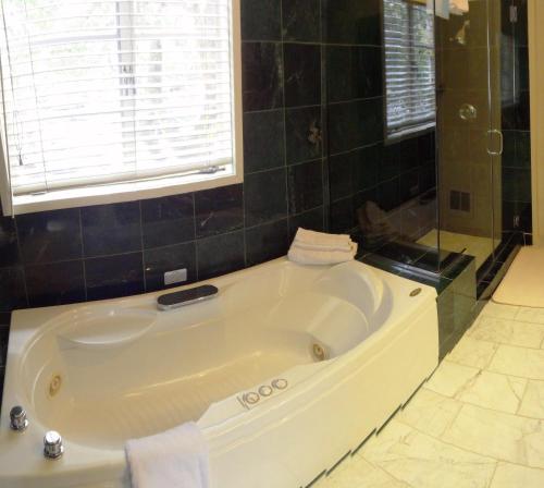 La salle de bains est pourvue d'une grande baignoire blanche et d'une fenêtre. dans l'établissement Tally Ho Inn, à Carmel