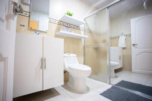 a bathroom with a toilet and a glass shower at MB Apartment - A in San Felipe de Puerto Plata