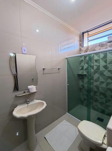 a bathroom with a shower and a sink and a toilet at Hotel Graunas in São Carlos