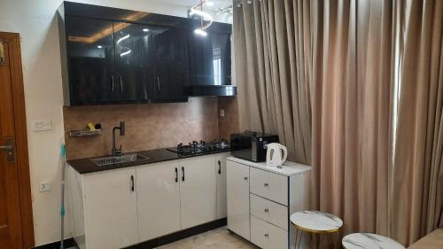 a small kitchen with white cabinets and a sink at 2 BHK Starry Night Penthouse in Islamabad