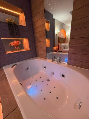 a large bath tub in a bathroom with a mirror at Luxury Jacuzzi Suites Halifax in Halifax