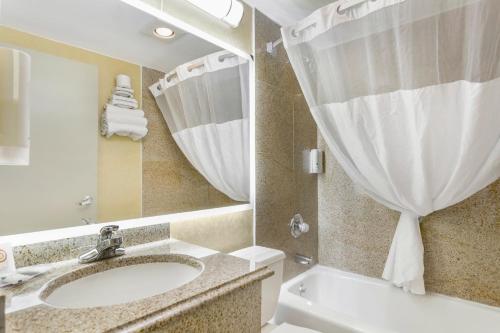 a bathroom with a sink and a mirror and a tub at Quality Inn JFK Airport Rockaway Blvd in Queens