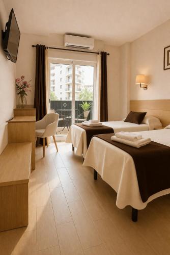 a hotel room with two beds and a balcony at Hotel Ancla in Oropesa del Mar