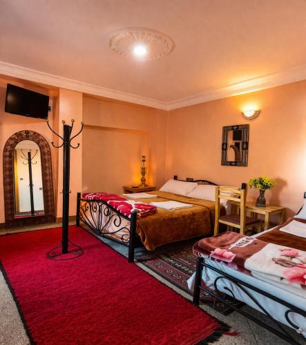 a bedroom with two beds and a red rug at Hôtel Restaurant BOUGAFER in Boumalne Dades