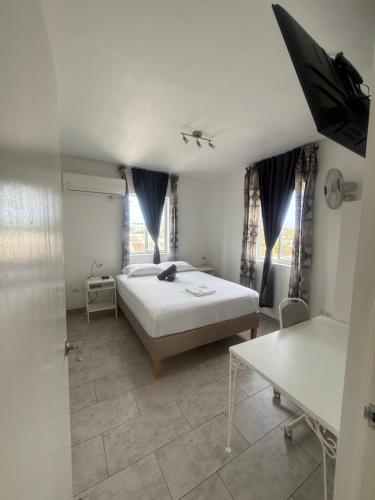 a bedroom with a bed and a table and windows at Downtown apartments in Kralendijk