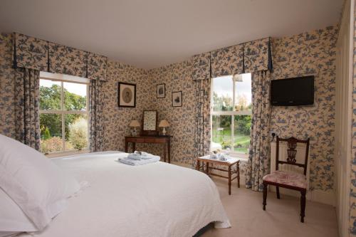 a bedroom with a bed and a tv on the wall at Rookwood Farmhouse B&B in Newbury