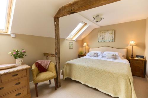 a bedroom with a large bed and a chair at Gooseyard at Middle Farm and Cottages in Picklescott