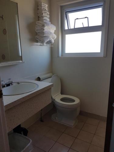 a bathroom with a toilet and a sink and a window at Alberni Inn in Port Alberni