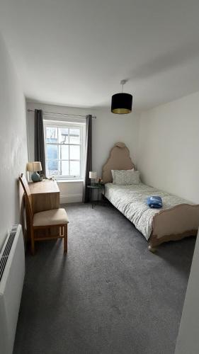 a bedroom with a bed and a chair and a window at The Teign Rooms in Teignmouth
