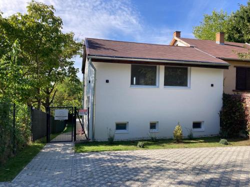 a white house with a black roof and a driveway at Sun&Fun Vendégház in Balatonakarattya