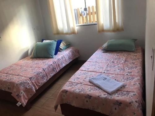 two beds in a room with two pillows on them at Riba House in Imbituba