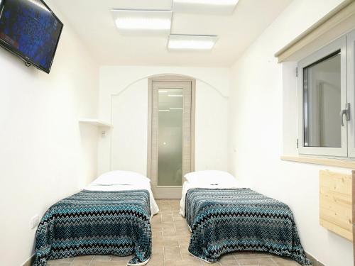 two beds in a room with white walls at Villa Tina ai Piedi del Faro di Leuca in Leuca