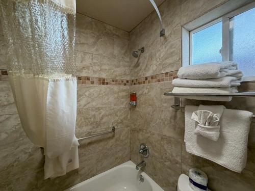 a bathroom with a shower curtain and a tub and a sink at SurfSide Stay in Morro Bay
