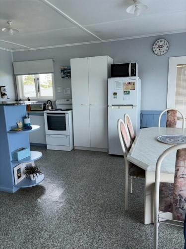 a kitchen with white appliances and a table with chairs at Raglan Vista in Raglan