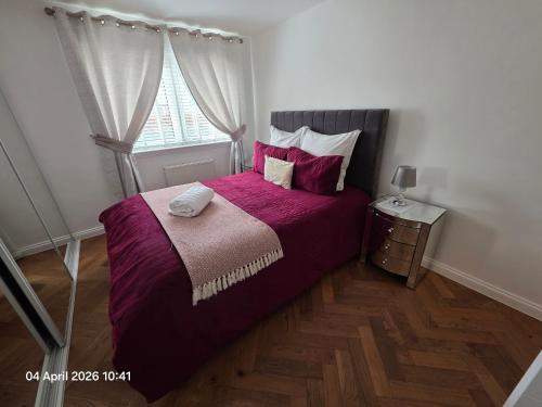 a bedroom with a bed with purple sheets and a window at Lovely 2 Bedroom Modern Ground Floor Flat in Clydebank