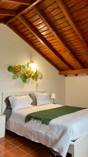 a bedroom with a white bed with a green comforter at Santo Cristo Loft in Lajes das Flores