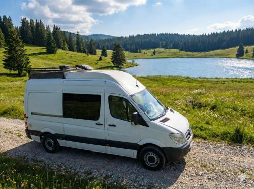 a white van parked next to a lake at Sprinter Camper Albania Rental in Tirana