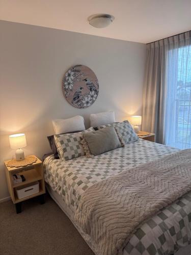 a bedroom with a bed and two lamps and a window at Beach Getaway in Mount Maunganui
