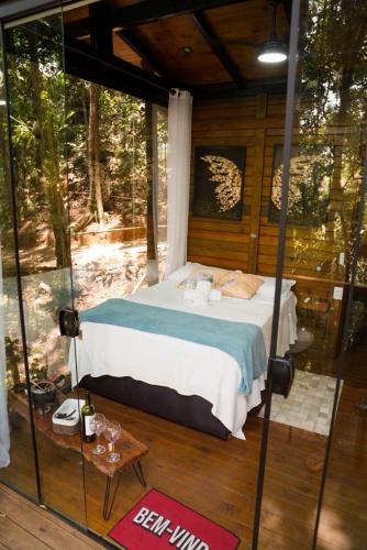a bed in a room with a glass wall at Tree House in Vítor Hugo