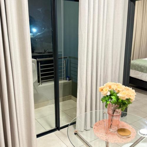 a vase of flowers on a glass table in a room at Kurhula nest in Midrand