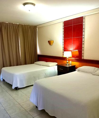 a hotel room with two beds and a red wall at Hotel Estrella in Managua
