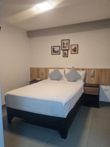 a bedroom with a bed with white sheets and pillows at Nivial Hotel in Tacna