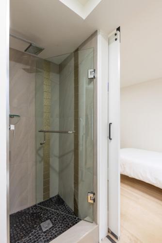 a glass shower door in a bathroom with a bed at Classic King Size Guest Suite with AC in Burnaby